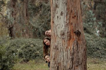 familia feliz jugando a las escondidas detrás de un árbol