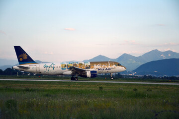 A Nile Air plane lands gracefully at Brașov Airport, Romania, with the scenic Carpathian Mountains...