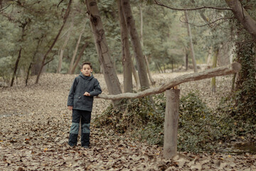 retrato de niño en un bosque con suelo de hojas caídas y secas en temporada de otoño