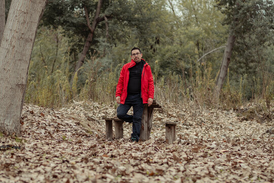 hombre posando en medio del bosque en unas bancas de camping en pleno oto&ntilde;o