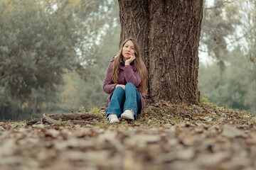 retrato de mujer sentada sobre las hojas caídas en medio del bosque en temporada de otoño