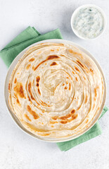 Indian flatbread paratha with raita sauce on white background, top view. Indian food.