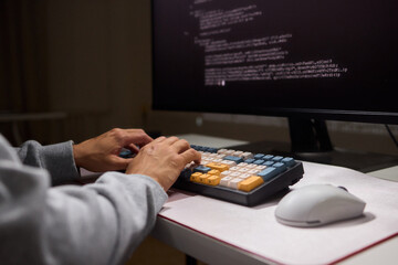 A young programmer codes intently in a dark setting, immersed in his work and creativity