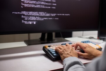 A young programmer codes intently in a dark setting, immersed in his work and creativity