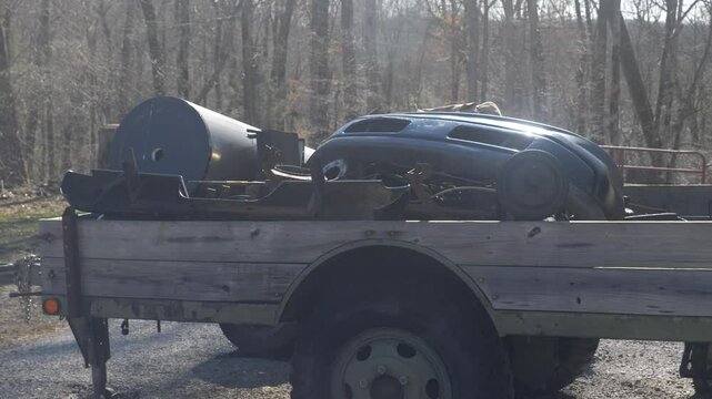Vintage car parts on a trailer in the woods