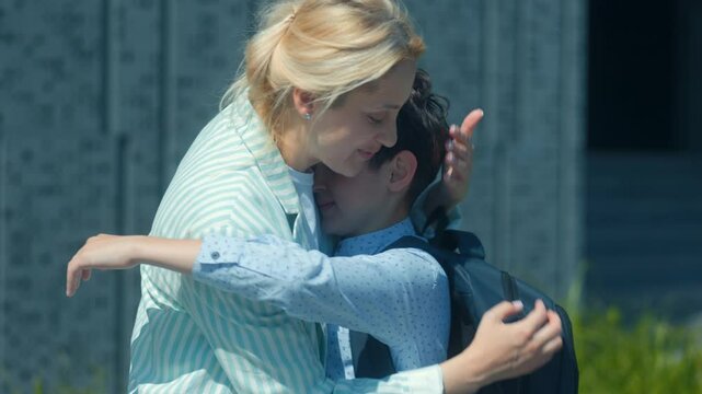 Mother Giving Son a Goodbye Kiss Before Entering School Building