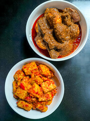 two white bowls filled with rich and flavorful Indonesian dishes