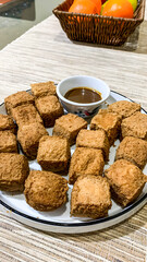 a plate piled high with numerous golden-brown fried tofu pieces