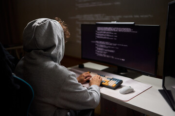 A young programmer codes intently in a dark setting, immersed in his work and creativity