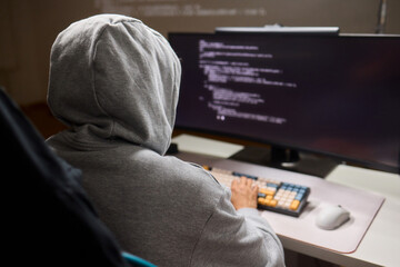 A young programmer codes intently in a dark setting, immersed in his work and creativity