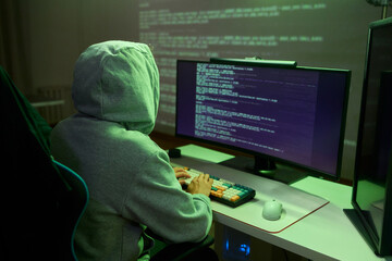 A young programmer codes intently in a dark setting, immersed in his work and creativity