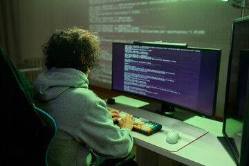 A young programmer codes intently in a dark setting, immersed in his work and creativity