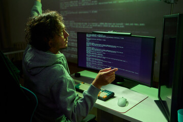 A young programmer codes intently in a dark setting, immersed in his work and creativity