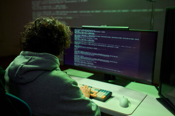 A young programmer codes intently in a dark setting, immersed in his work and creativity
