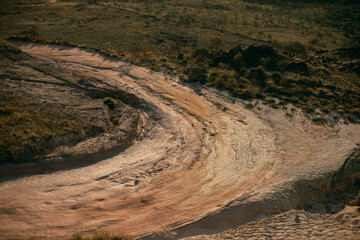 Curved path with dry and cracked soil, crater.
