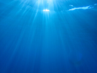 Ocean blue underwater with sunrays, Underwater Sea Deep Water Abstract Sunshine, sea wave , clean waters in summer time, Natural underwater seascape, sand on ocean floor and water surface with sunligh