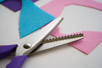 The scissors rest on the felt scraps. Embroidery and stitching.