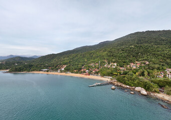Fototapeta premium Aerial view of the coastal region in Ilhabela, featuring forested cliffs, rocky shoreline, and deep blue sea