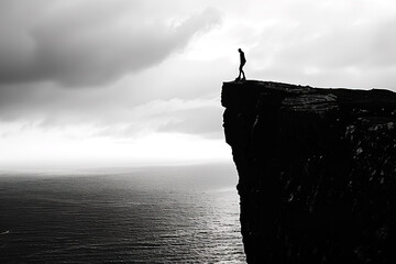 Cliff's Edge: Silhouette of a person stands on the precipice overlooking ocean