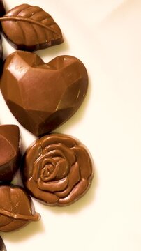 Top view of various kind of dark brown chocolate pieces on plate.