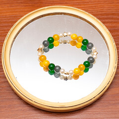 Colorful beaded bracelet displayed on a round mirror, showcasing vibrant hues and elegant design...