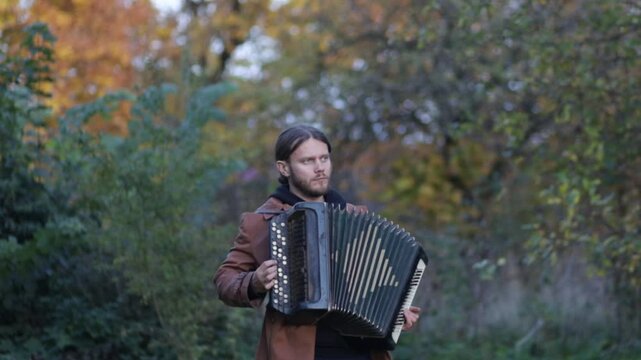 a man plays the accordion in an autumn garden