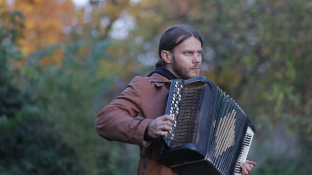 a man plays the accordion in an autumn garden