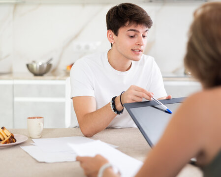 Woman manager tells guy client about specifics of design of microloan, about benefits and advantages. Female seller draws up contract on laptop