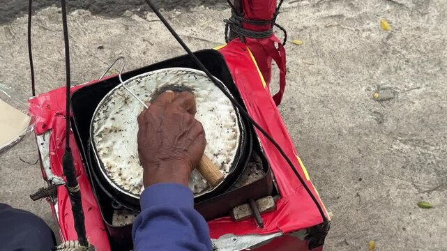 Street vendor preparing kue cubit &mdash; a popular Indonesian mini pancake snack cooked fresh on the roadside, loved for its soft texture and nostalgic flavor. Karet, Indonesia - June 25, 2025