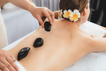 Hot stone massage at spa salon in luxury resort with day light serenity ambient, blissful woman...