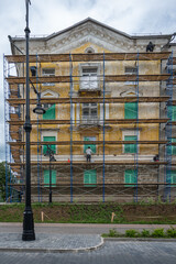 An old building in scaffolding during renovation and painting of the facade.