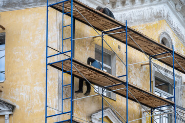 An old building in scaffolding during renovation and painting of the facade.