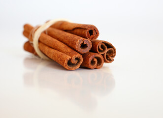 Cinnamon sticks on white reflective background. Selective focus. Macro.