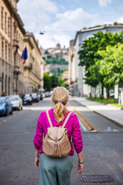 Fototapeta Woman tourist walking on street in lower town, Bergamo, Italy. City break and exploration during summer vacation in Europe