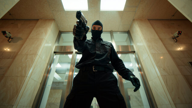 A thief dressed in black with gloves and a ski mask aims a gun while standing in a corridor of a modern building. Security cameras are visible above. Crime and robbery concept. Generative AI.