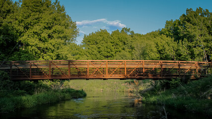 Fototapeta premium a beautiful bridge scene stretched over a reflective creek or stream. footbridge on a sunny day. midwest united states