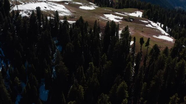 Aerial view of snow-felled mountains and valleys in Siri Paye in Pakistan, with dense plants