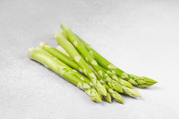 Bunch of raw fresh green asparagus stalks on light gray textured background. Healthy food, fresh...
