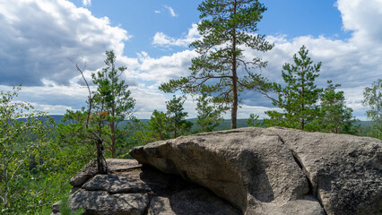 Small Devils rock, Devil's Hillfort complex on sunny summer day. Iset Park, Iset village, Sverdlovsk region, Russia. Hiking. Pine trees on rock