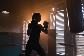 Women self defense girl power. Strong woman fighter training punches on boxing ring. Healthy strong girl punching boxing bag. Training day in boxing gym. Strength fit body workout training