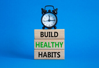 Healthy habits symbol. Concept word Build Healthy habits on wooden blocks with alarm clock....