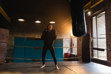 Women self defense girl power. Strong woman fighter training punches on boxing ring. Healthy strong girl punching boxing bag. Training day in boxing gym. Strength fit body workout training
