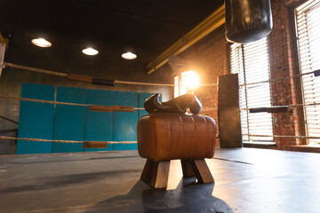 Boxing gloves lying down on boxing ring in empty gym. Equipment for fight training competition black protective boxing gloves ready for fighter winner on ring. Strength fit body workout training