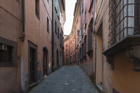 Fototapeta Narrow empty street with old colorful buildings in historic center of Barga, Tuscany, Italy.