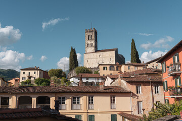 Scenic view of historic buildings and church tower in Barga, Tuscany, Italy under blue sky.