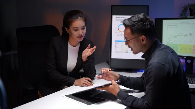 business, deadline and technology concept - coworkers working with charts on computer screen and papers late at night office
