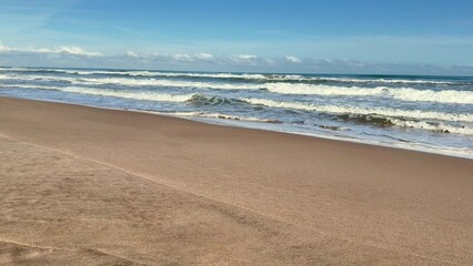 A tranquil beach view showcasing gentle waves lapping against soft sand beneath a clear blue sky overhead
