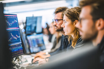 People analyzing stock market data on computer screens in a financial trading office