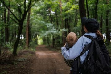 
Nature walk with baby, peaceful moment in the fresh air, family bonding in the forest. Mom holding baby in her arms while walking in the forest