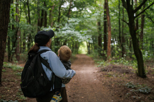 
Nature walk with baby, peaceful moment in the fresh air, family bonding in the forest. Mom holding baby in her arms while walking in the forest